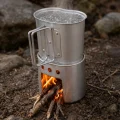 Silver cooking cup boiling water on a wood burning canteen stove outdoors