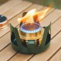 Alcohol stove burning with blue and yellow flame inside metal pot support on an outdoor table