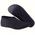 Pair of black swim shoes with one showing the flexible upper and the other displaying the grippy outsole