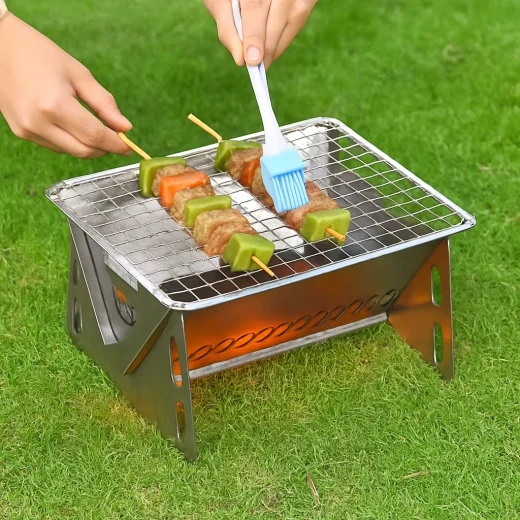 Mini BBQ grill for hiking used outdoors on grass cooking skewers
