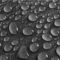 Water droplets beading on waterproof black nylon poncho fabric
