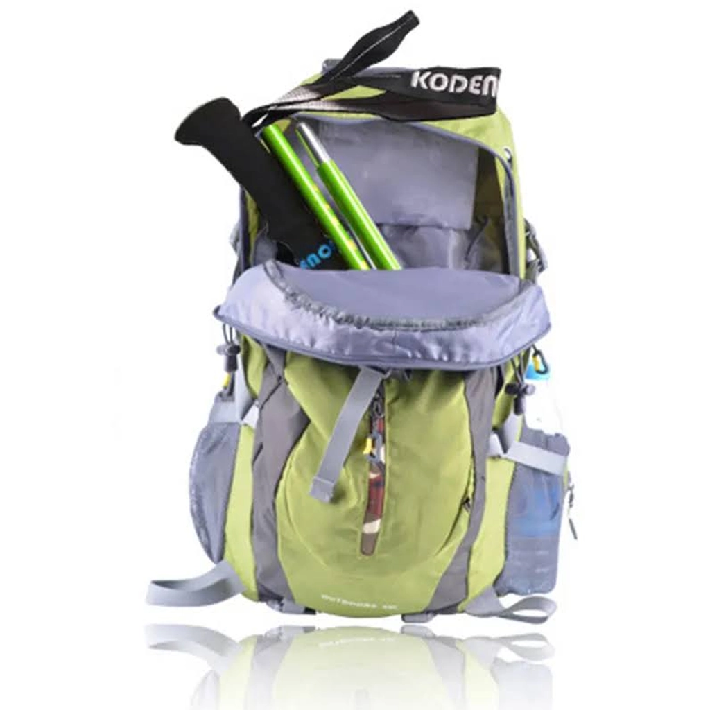 Folded green trekking pole stored inside the front pocket of a hiking backpack