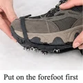 Hands fitting the front section of a black ice grip over the toe of a hiking shoe
