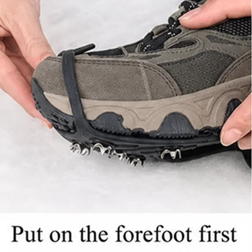 Hands fitting the front section of a black ice grip over the toe of a hiking shoe