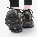 Hiking shoe raised to show the black traction grip and stud arrangement on snow