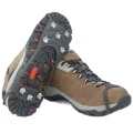 Pair of black studded ice grips fitted over brown hiking shoes