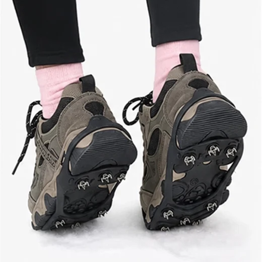 Rear view of black ice grips fitted to hiking shoes while walking on snow